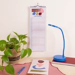 A spiral-bound September desk calendar hangs on a wall above a desk setup.