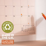 Calendar with a pen on a light surface, featuring a 'Recycled Paper' label and text about UK production and plastic-free packaging.