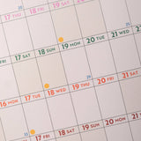 Calendar with dates highlighted in different colors on a light gray background