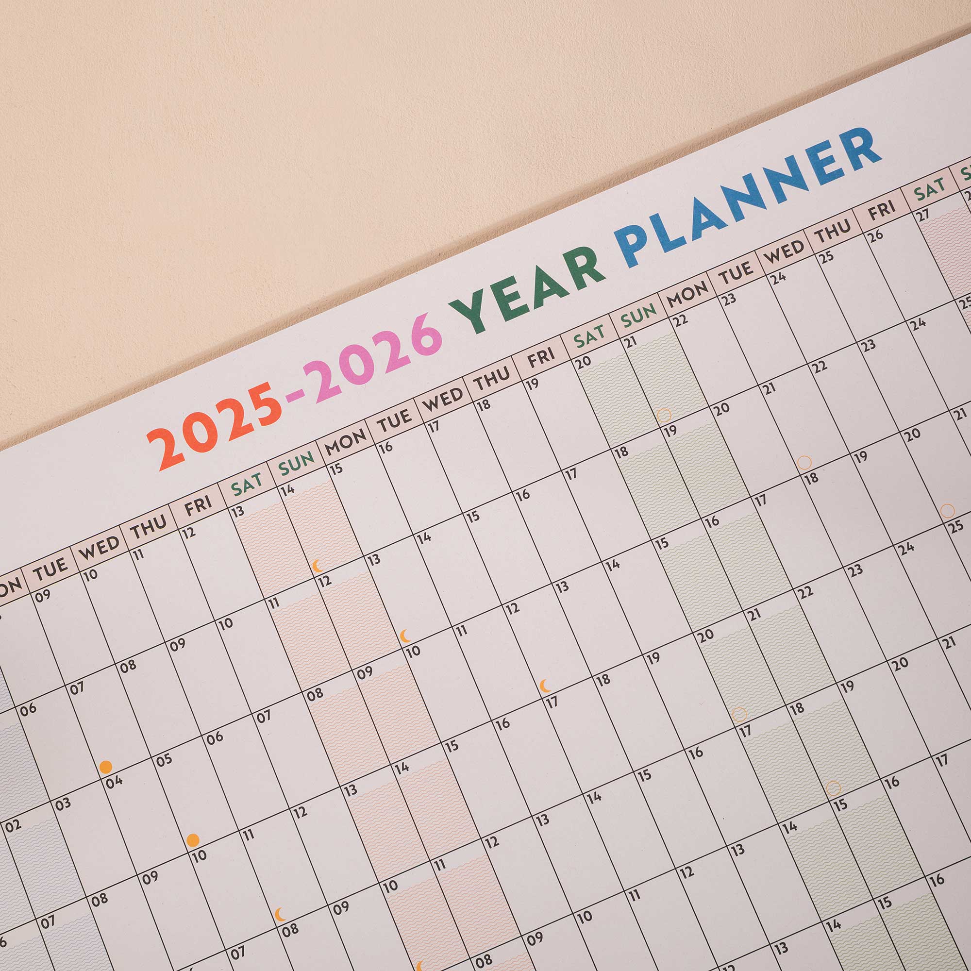 close up of academic wall planner showing highlighted weekends and moon phases