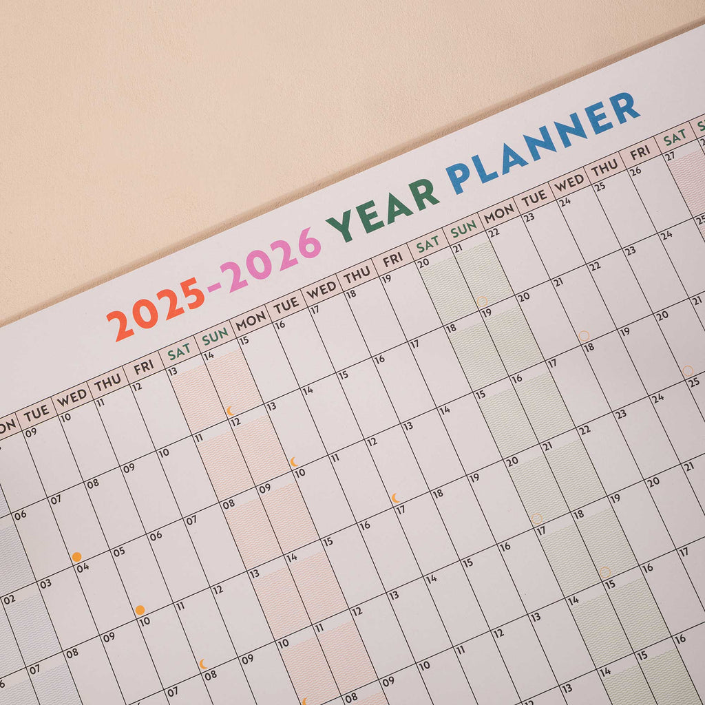 close up of academic wall planner showing highlighted weekends and moon phases