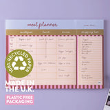 Meal planner with shopping list on a purple background, featuring recycled paper and plastic-free packaging text.