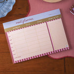 Meal planner and shopping list pad on a wooden surface