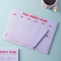 Lilac and Plum A4 weekly planner pad with a pen and coffee on a light blue background