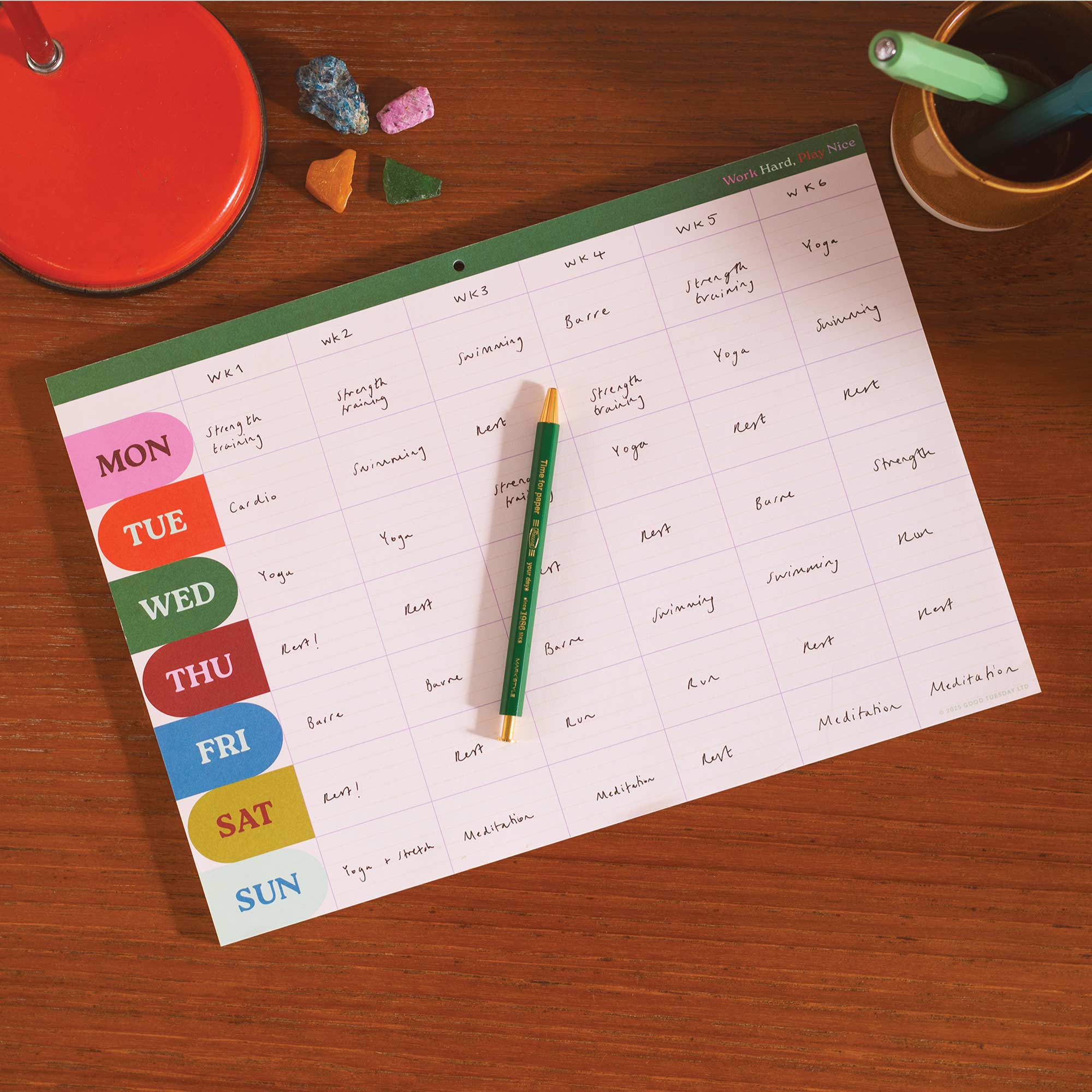 Work Hard Play Nice planner pad styled on a desk with pens
