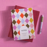 Colorful diamond patterned notebook with 'NOTES' text on a pink background