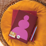 Two notebooks with a purple design on a yellow cushion