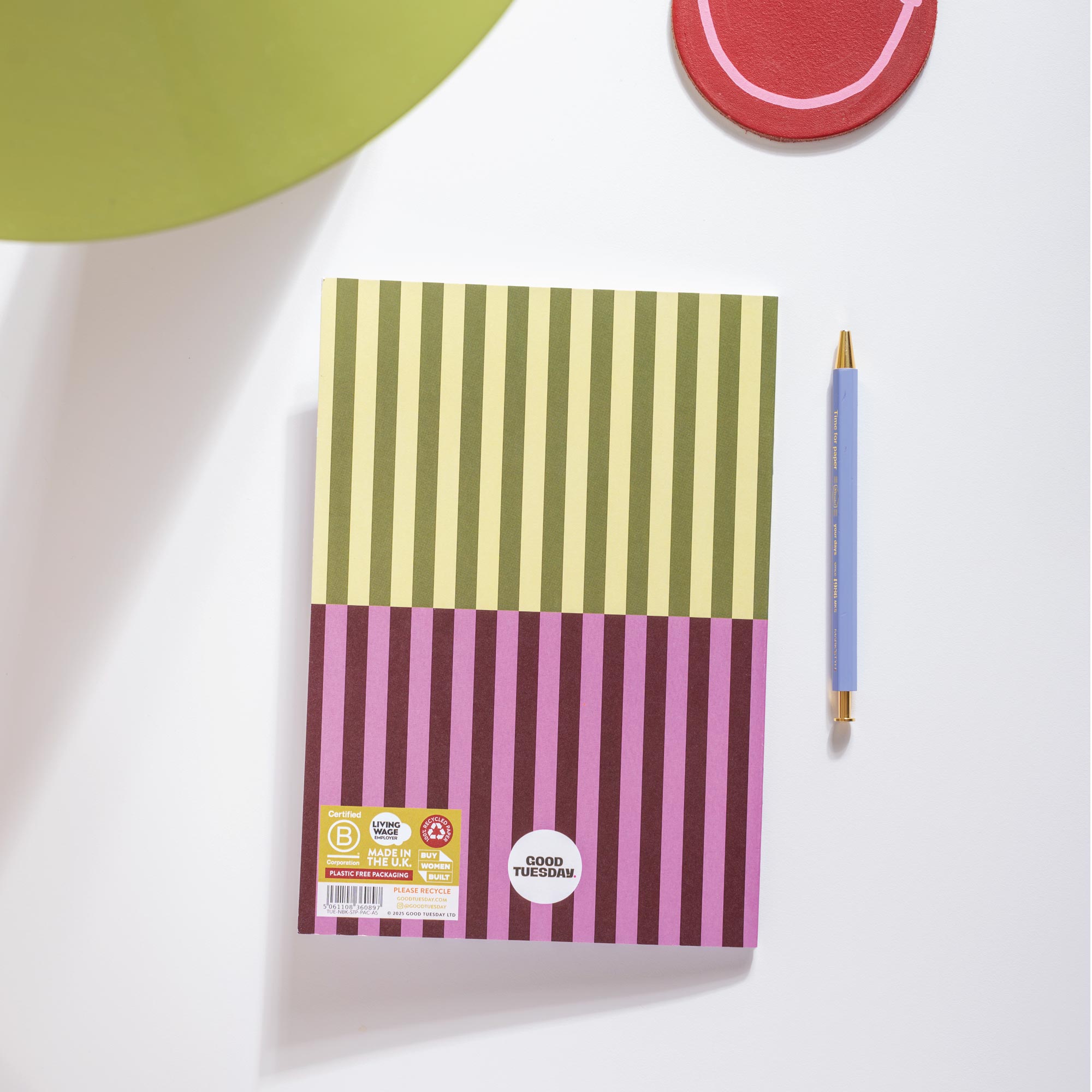 Notebook with striped design on a white surface with a pen next to it
