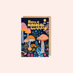 Greeting card with colorful mushrooms and flowers and text 'Have a Magical Birthday' on a white background.