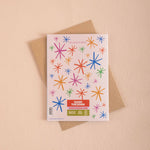 Greeting card with colorful star patterns and a brown envelope on a beige background