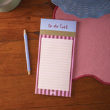 Notepad with 'to do list' on a wooden surface with a pen and cloth.