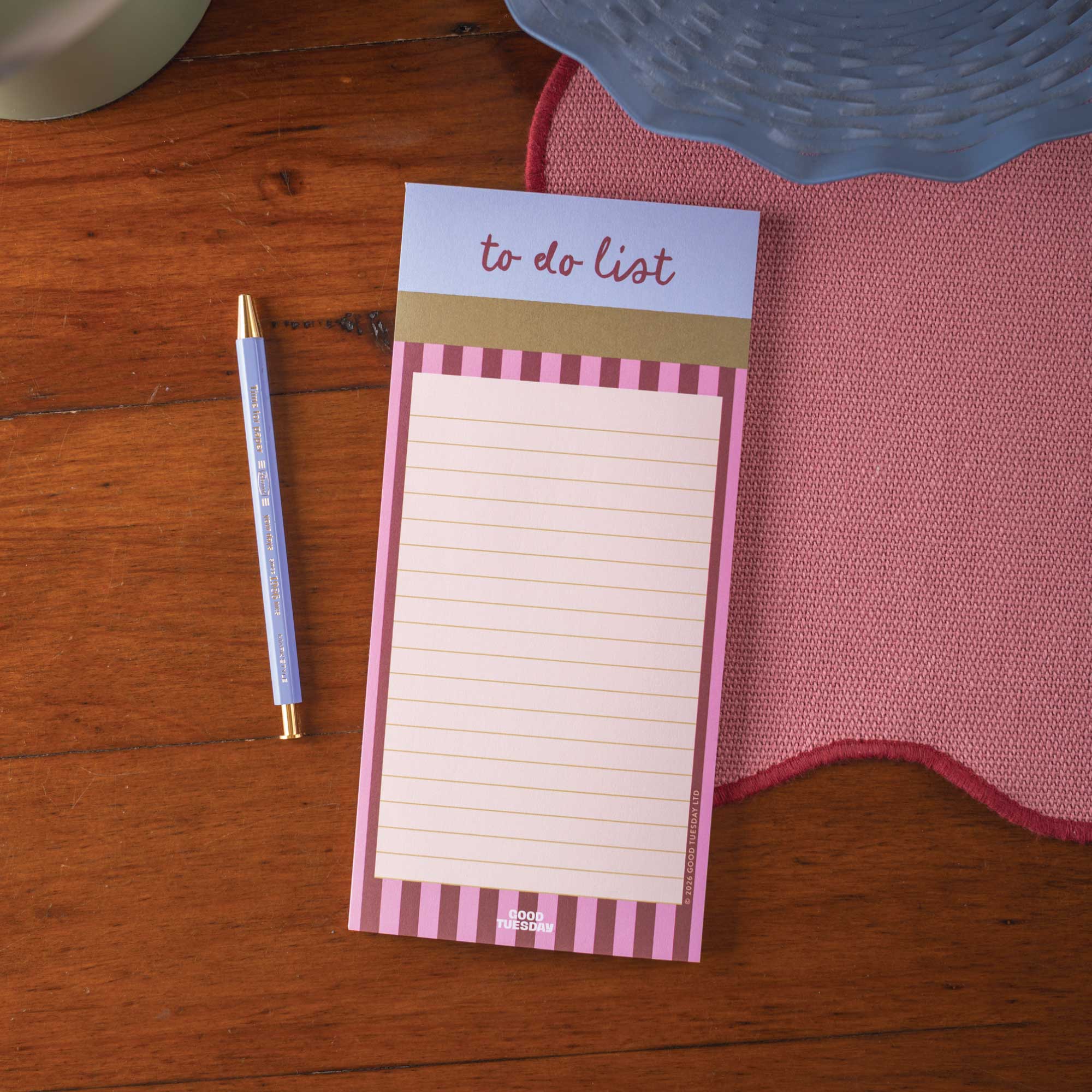 Notepad with 'to do list' on a wooden surface with a pen and cloth.