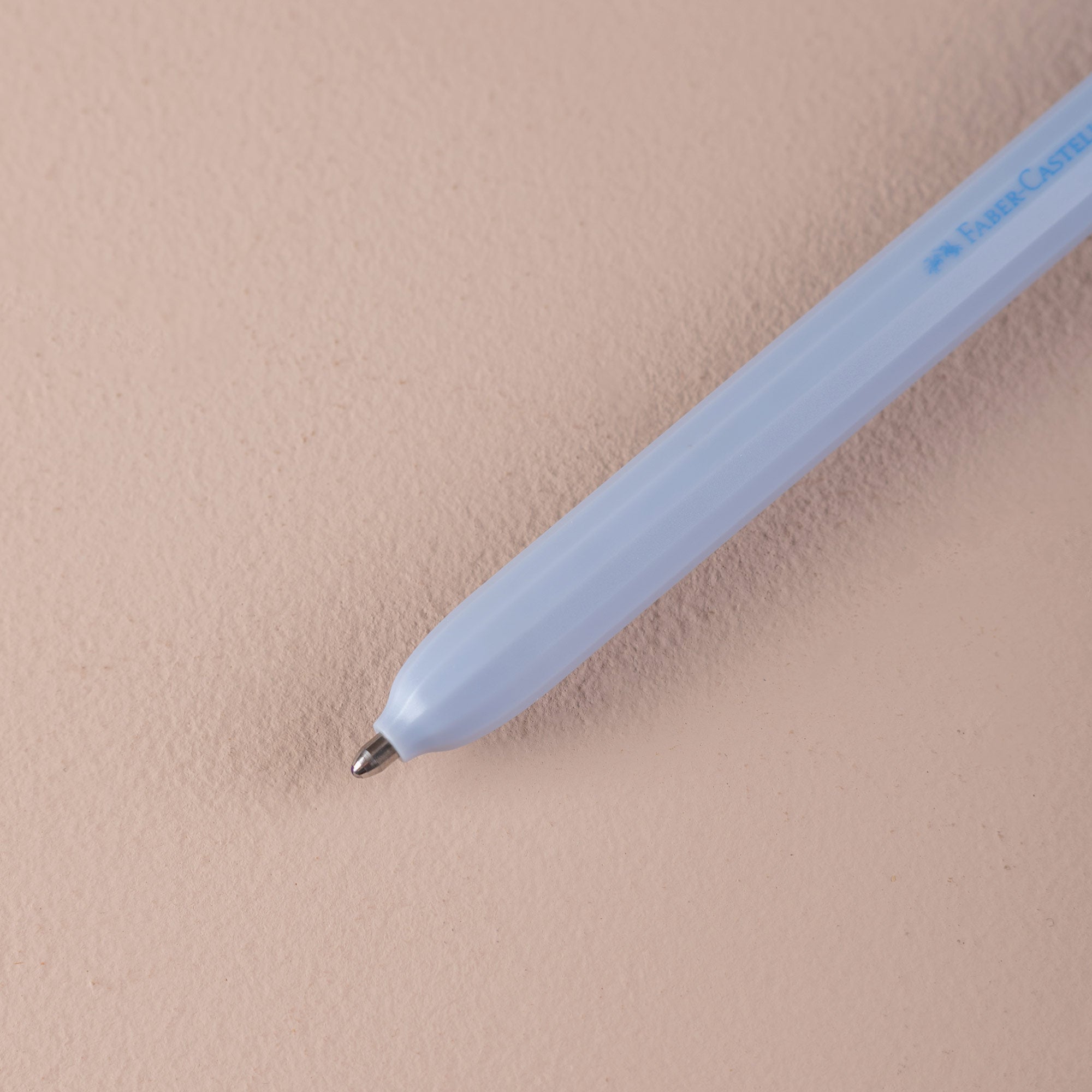 Light blue ballpoint pen on a beige surface