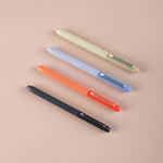 Four colourful ballpoint pens (black, orange, blue, and green) on a beige background