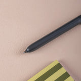 Black pen on a beige surface with a striped notebook