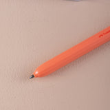 Orange ball point pen on a beige surface