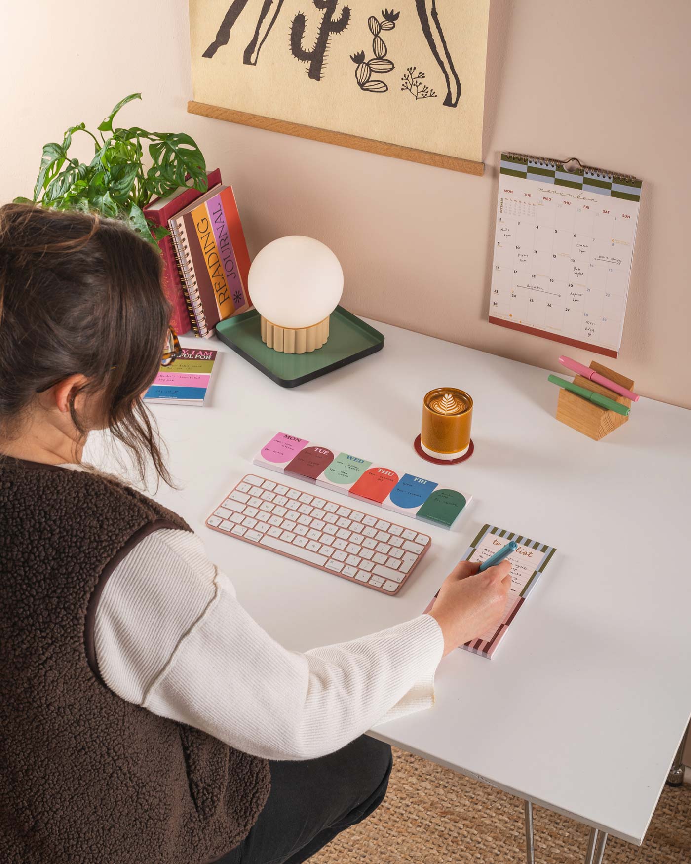 Person working at a desk with a keyboard, notebook, and various items on a white desk.