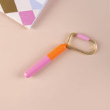 Mini pen on a gold key chain in colours  Orange and Pink on a beige background