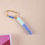 Mini pen on a gold key chain in colours  Turquoise and Blue on a beige background