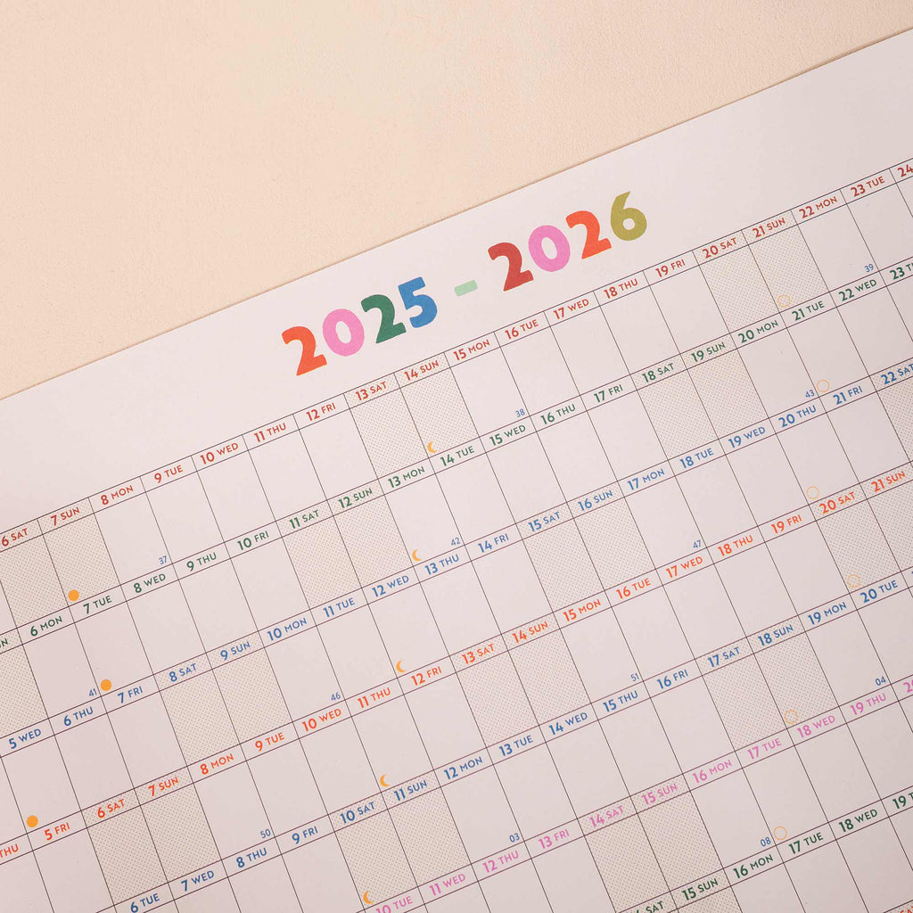 close up of academic wall planner showing highlighted weekends, moon phases and week numbers