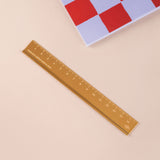 Brass ruler on a beige surface with a checkered pattern in the background