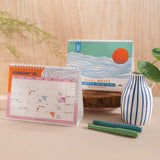 Front cover of the 2025–2026 Academic Desk Calendar – Ocean Tidal Waves design with abstract blue waves and orange sun, printed on 100% recycled paper